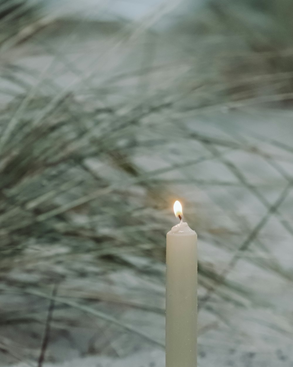 a single white candle with a blurry background