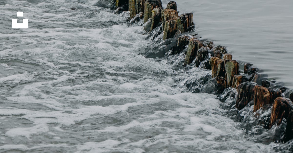 A long line of rocks sitting in the middle of a body of water photo ...