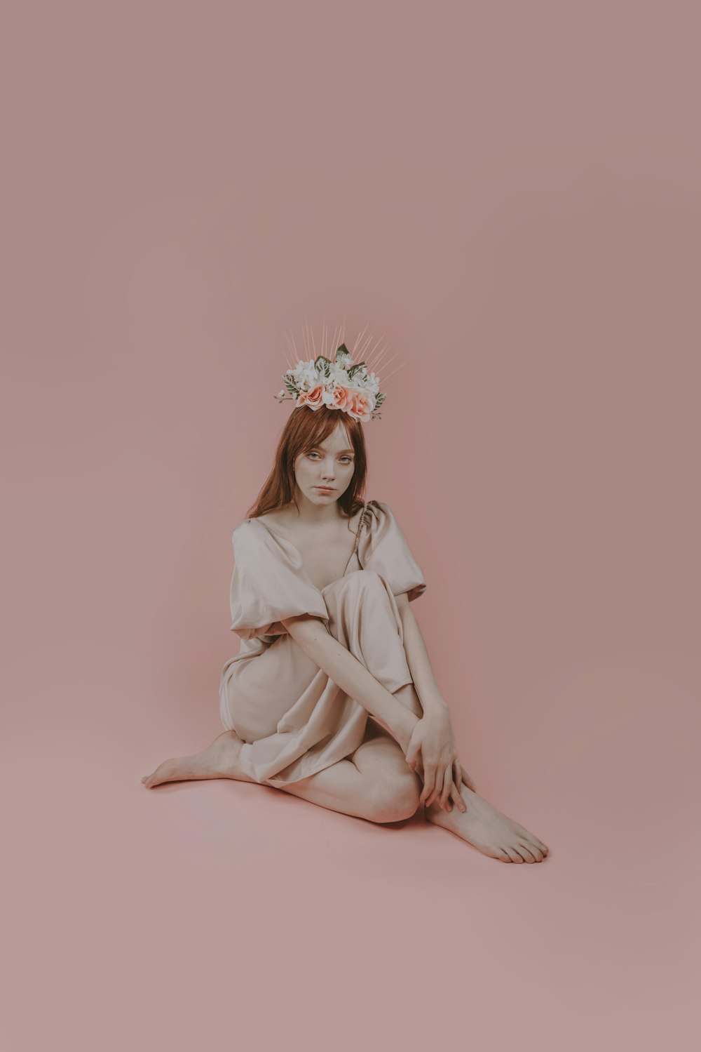 a woman sitting on the ground wearing a flower crown