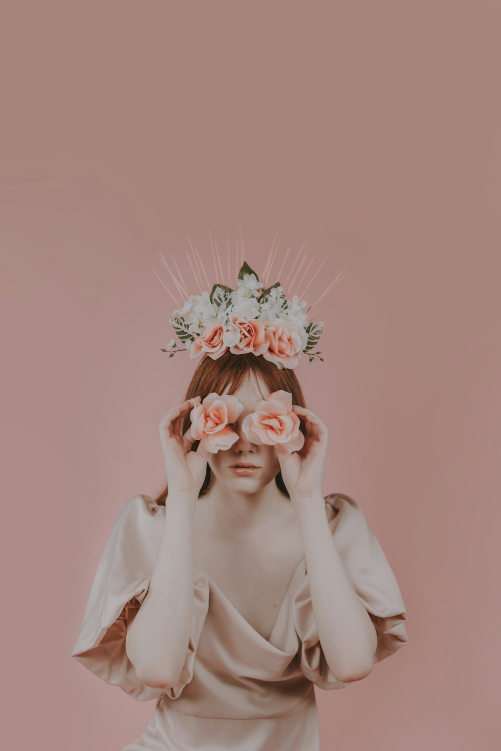 a woman with flowers on her head covering her eyes