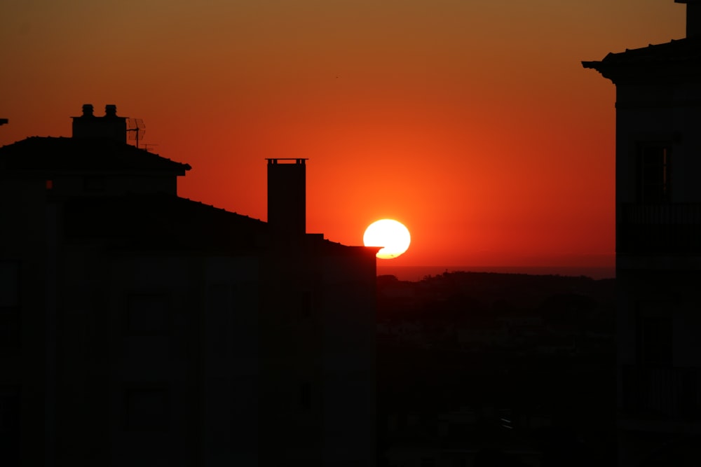 the sun is setting over a city with tall buildings