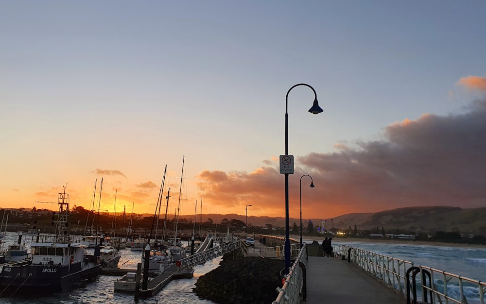 a dock with many boats in the water at sunset