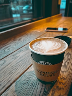A coffee cup next to a smartphone showing notifications from paying customers.