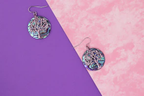 a pair of earrings sitting on top of a purple and pink surface