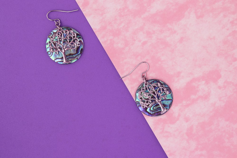 a pair of earrings sitting on top of a purple and pink surface