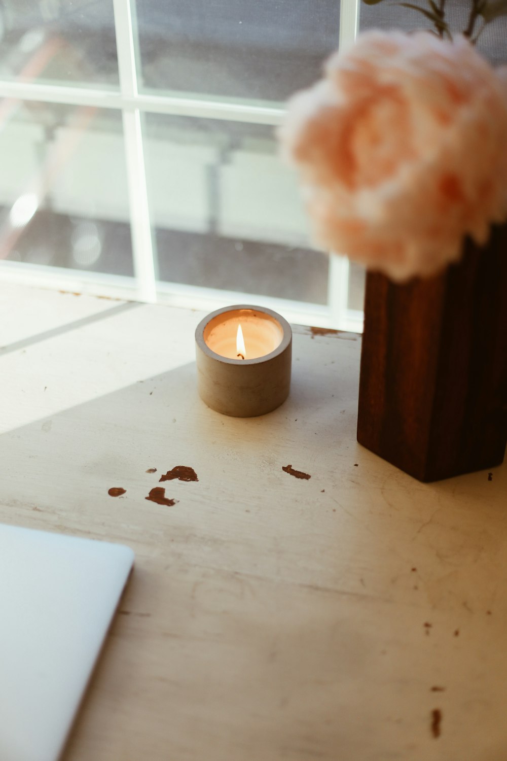 a candle sitting on a table next to a vase with a flower
