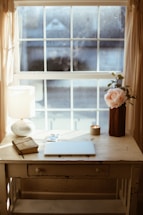 a desk with a laptop and a flower in a vase