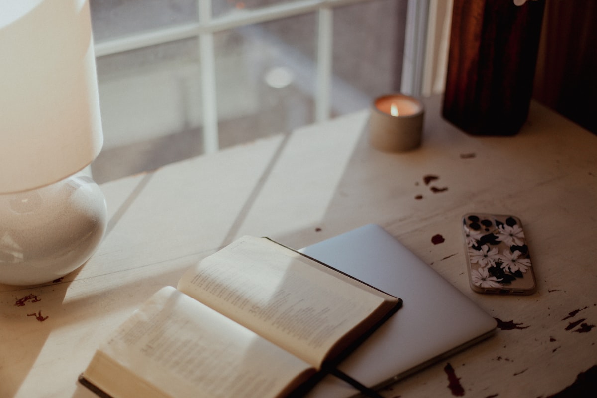 Open book on a table next to a soft candle, intimate end-of-week reflection