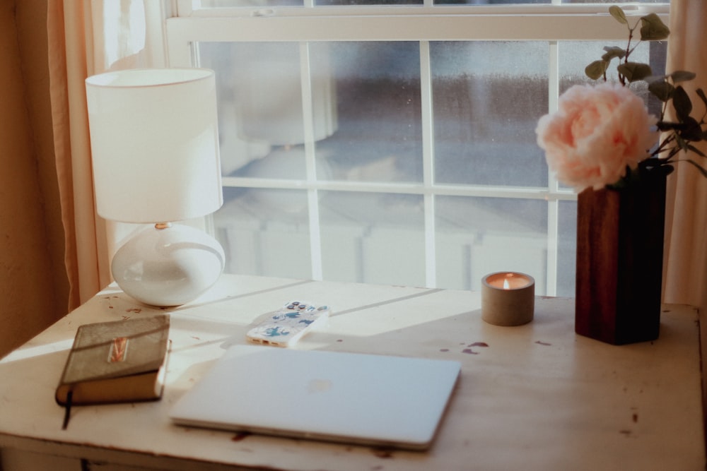 a laptop computer sitting on top of a desk next to a window