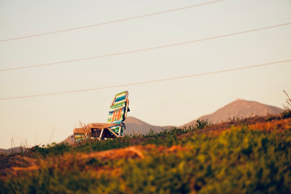 a lawn chair sitting on top of a lush green hillside