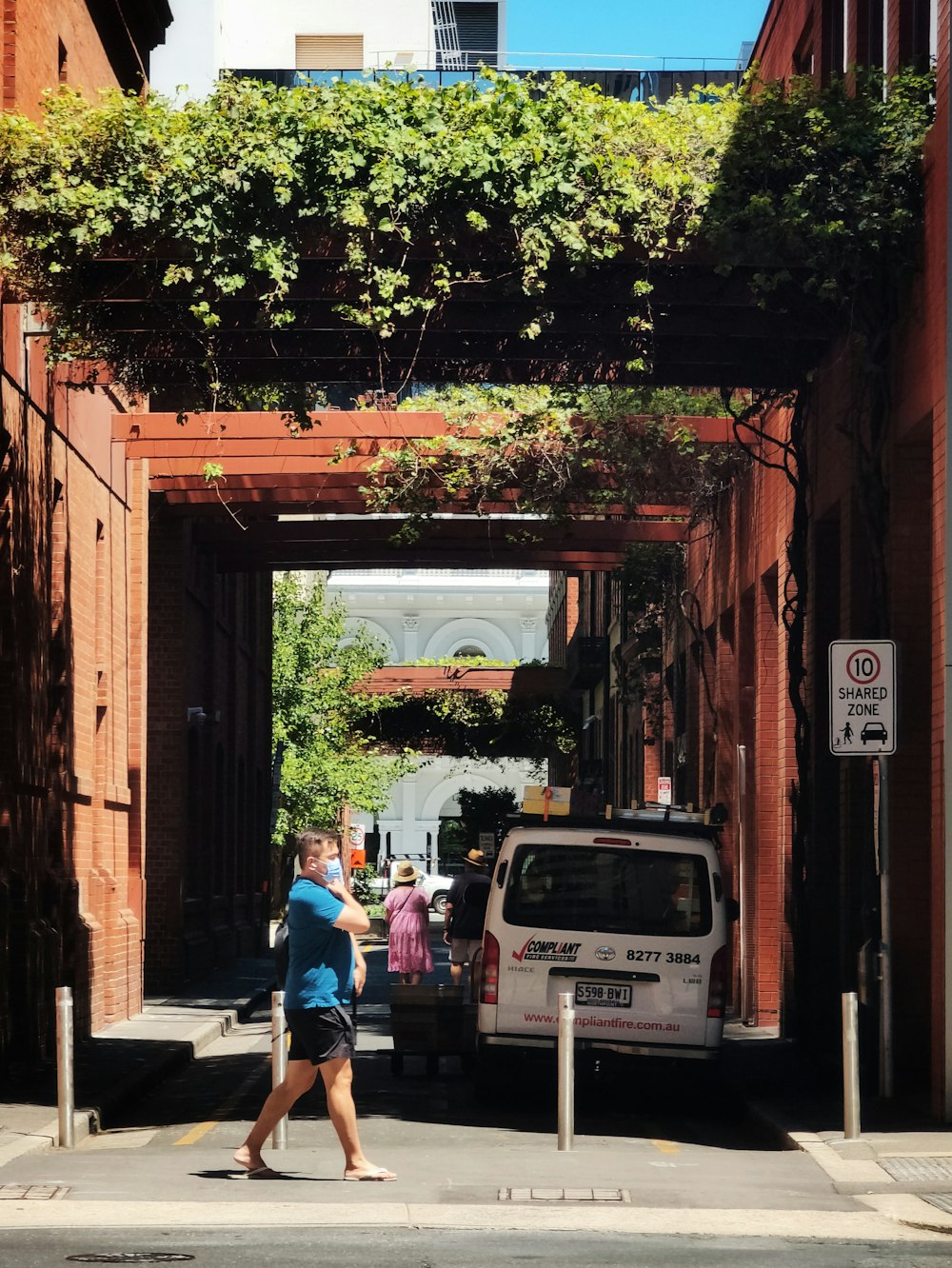 a woman walking down a street next to a white van