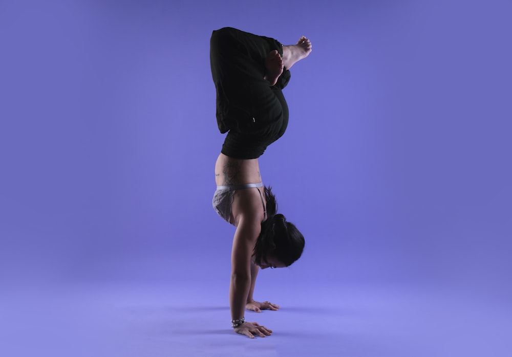 uma pessoa que faz um handstand em um fundo roxo