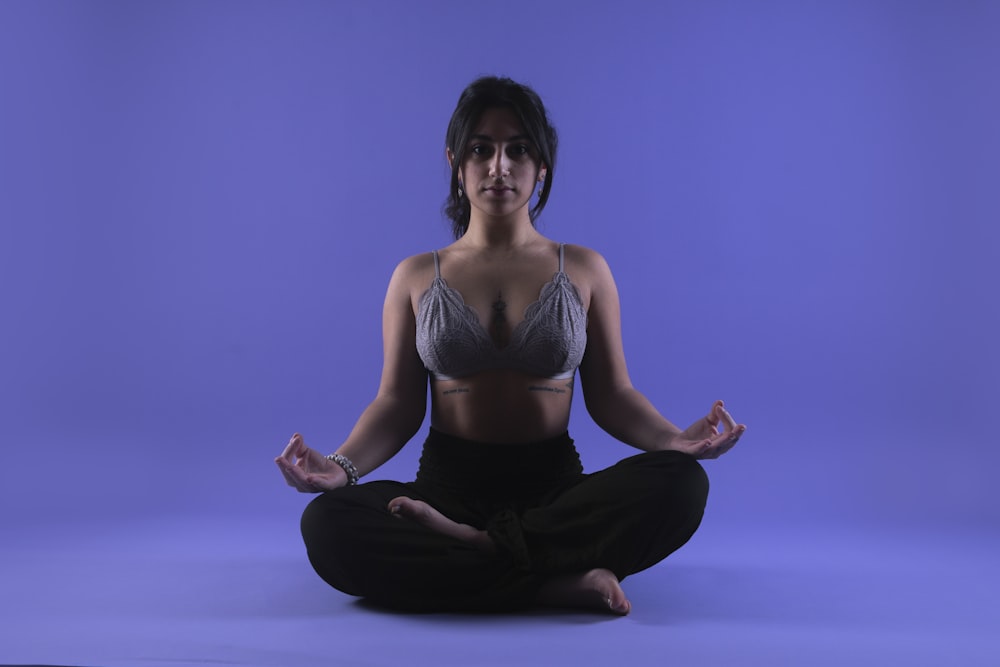 a woman in a bra top sitting in a yoga pose