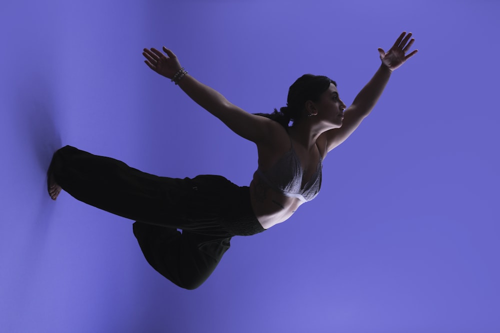 a woman jumping in the air with her arms outstretched