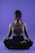 A person is sitting in a meditative pose with legs crossed on a smooth purple background. Their eyes appear closed, and they seem relaxed and focused. The lighting highlights the contours of their face and upper body, casting soft shadows.