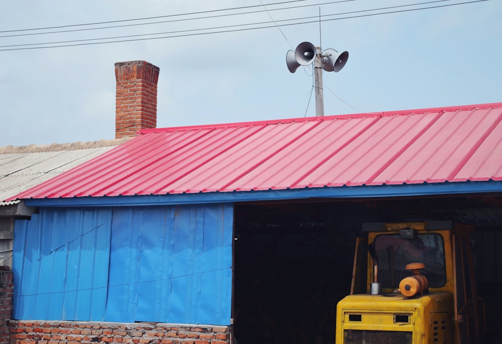 a yellow bulldozer in a garage with a red roof