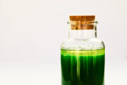 a bottle filled with green liquid on top of a table