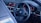A car interior showcasing a sleek steering wheel with the BMW logo and advanced digital dashboard. The dashboard displays various controls and information with bright, colorful graphics. The interior design features a modern and technological aesthetic.