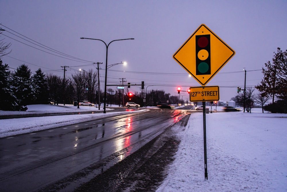 um semáforo sentado ao lado de uma estrada coberta de neve