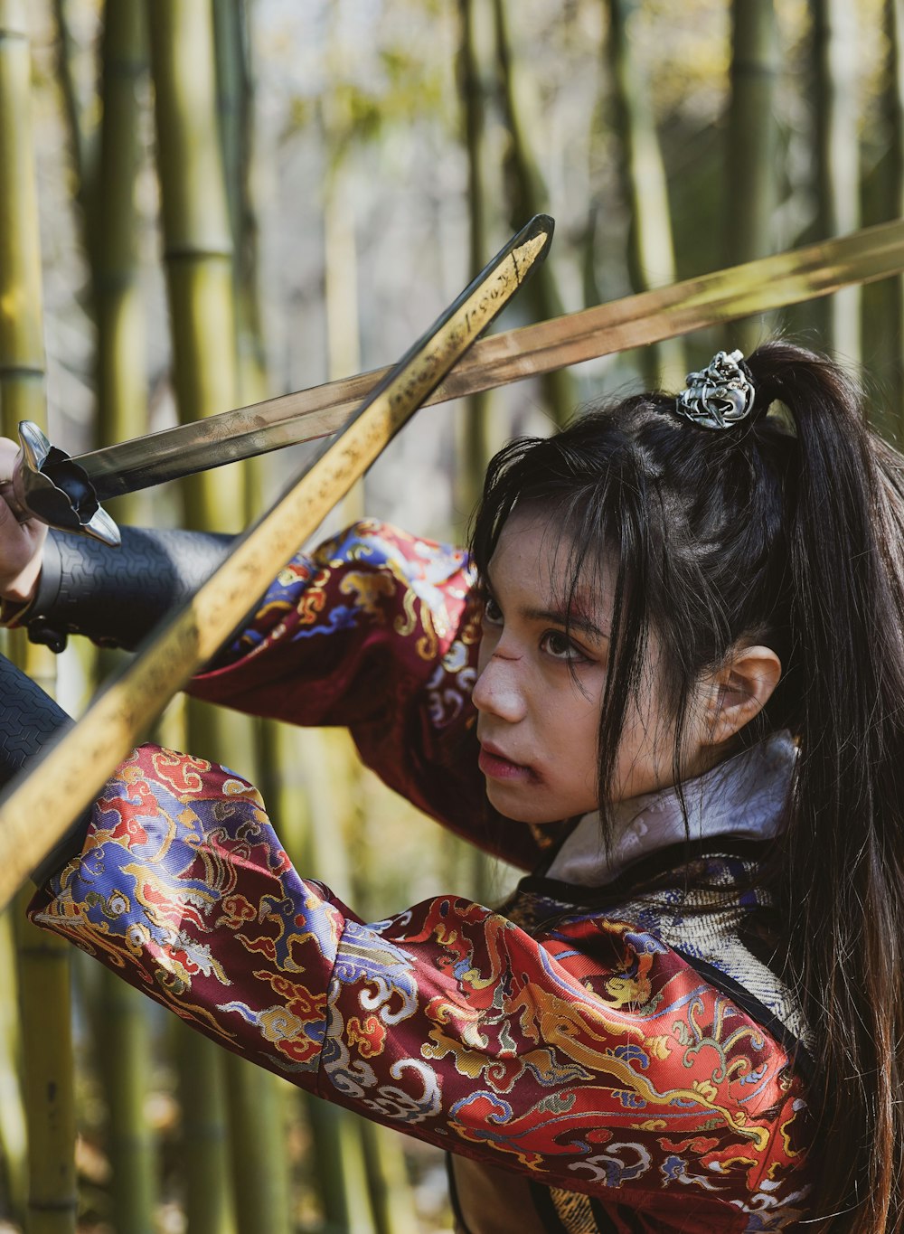 a young girl dressed in traditional chinese clothing holding two swords