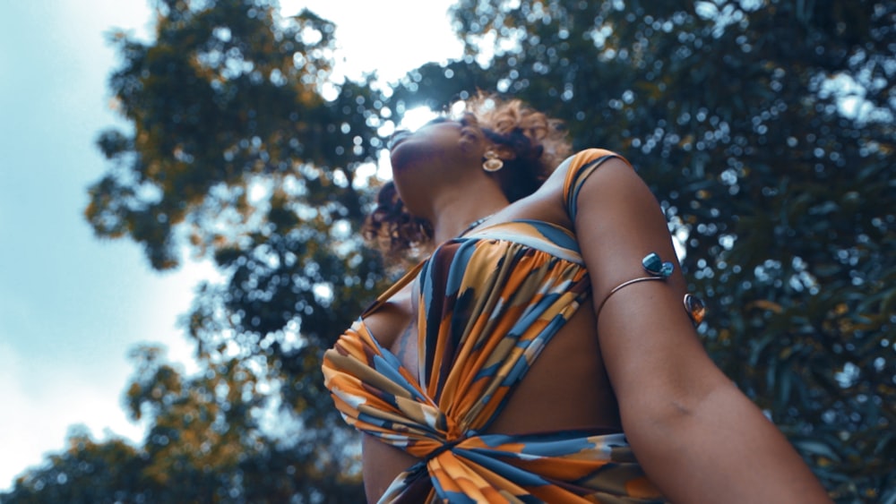 a woman in a colorful dress looking up into the sky