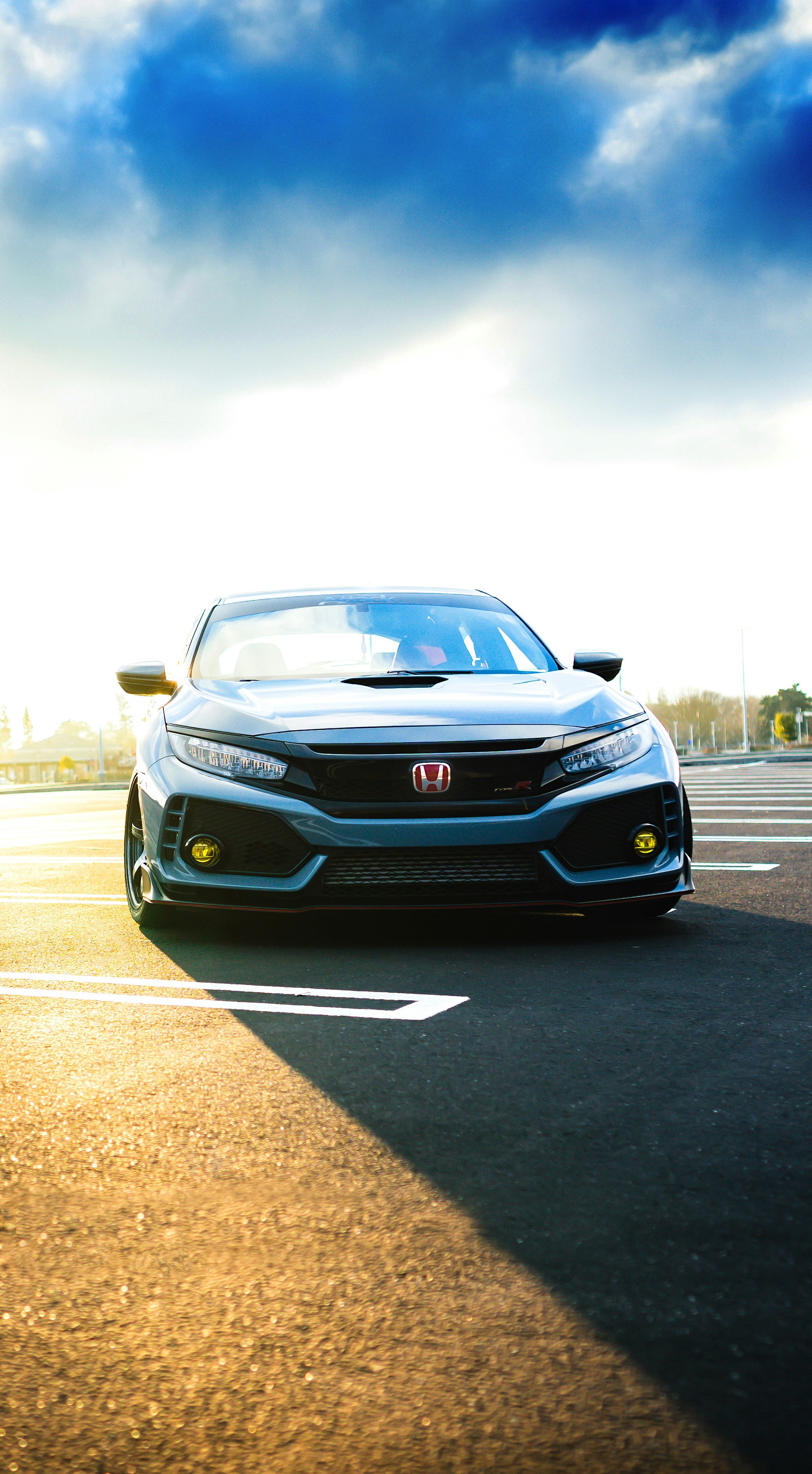 a silver car driving down a street next to a parking lot