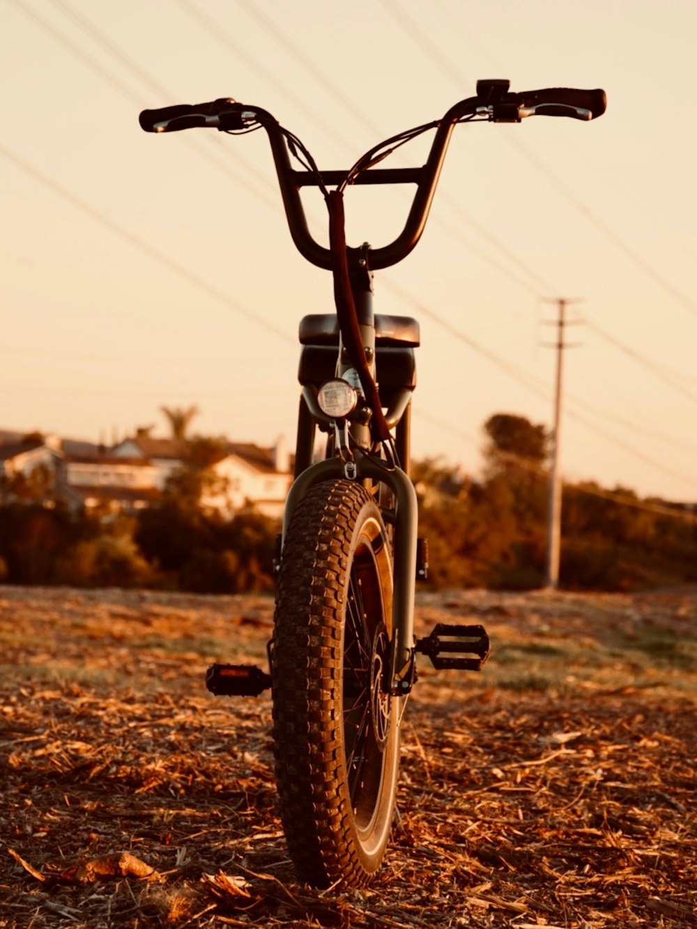 a bicycle parked in a field with power lines in the background