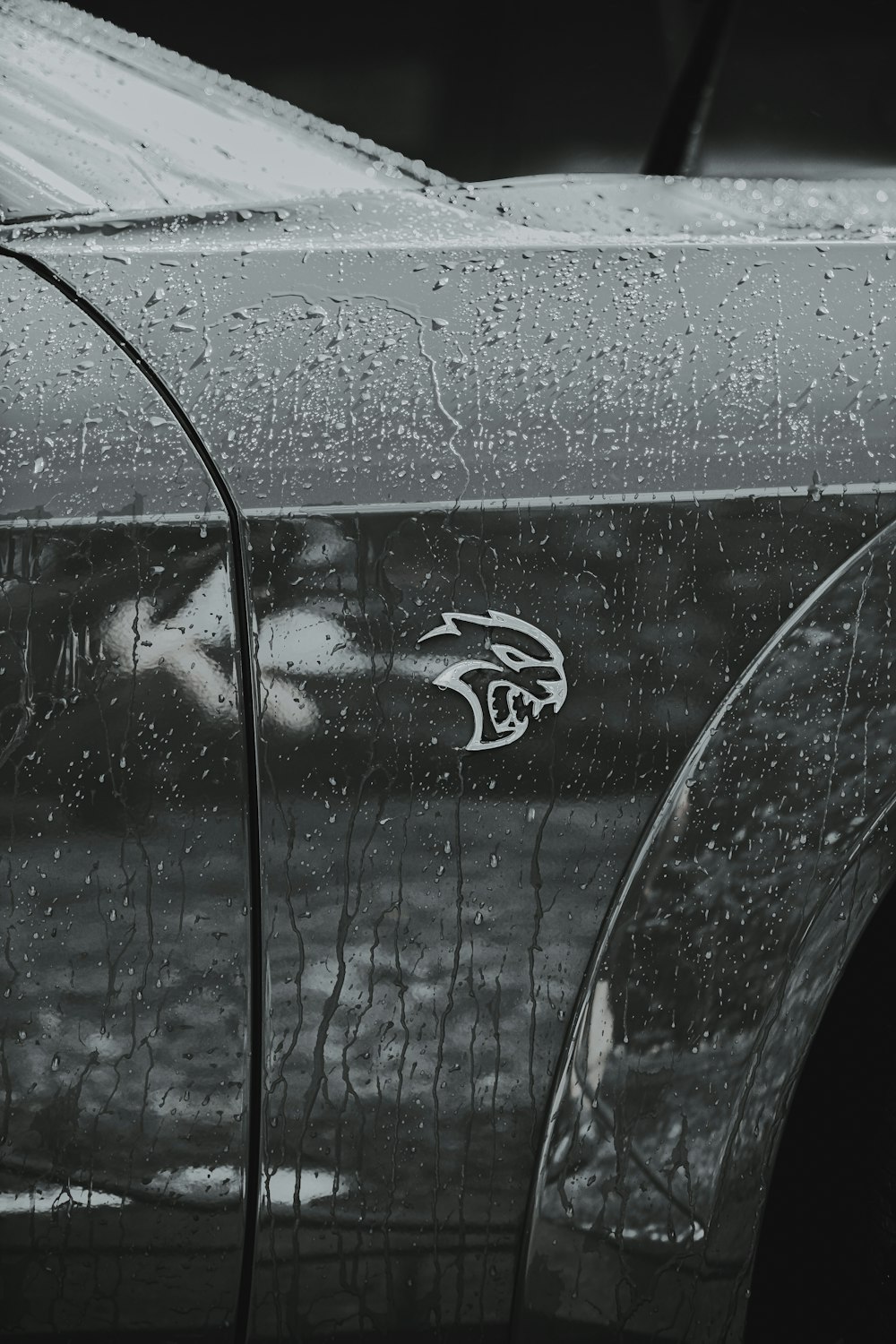 a black and white photo of a car with rain drops on it
