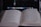 An open book with text in a non-Latin script is in focus, placed in front of a blurry, dark-screened laptop with visible icons and text.