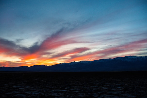 A dramatic sunset behind mountains, filling the sky with colors.