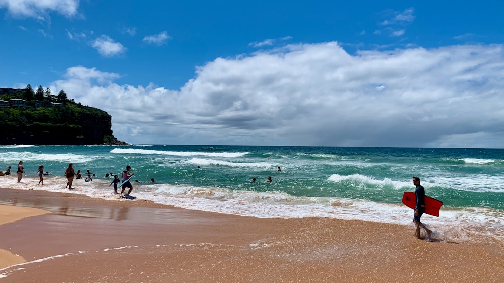 a group of people standing on top of a beach next to the ocean