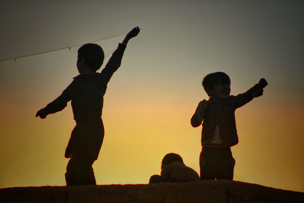 a couple of kids standing on top of a hill