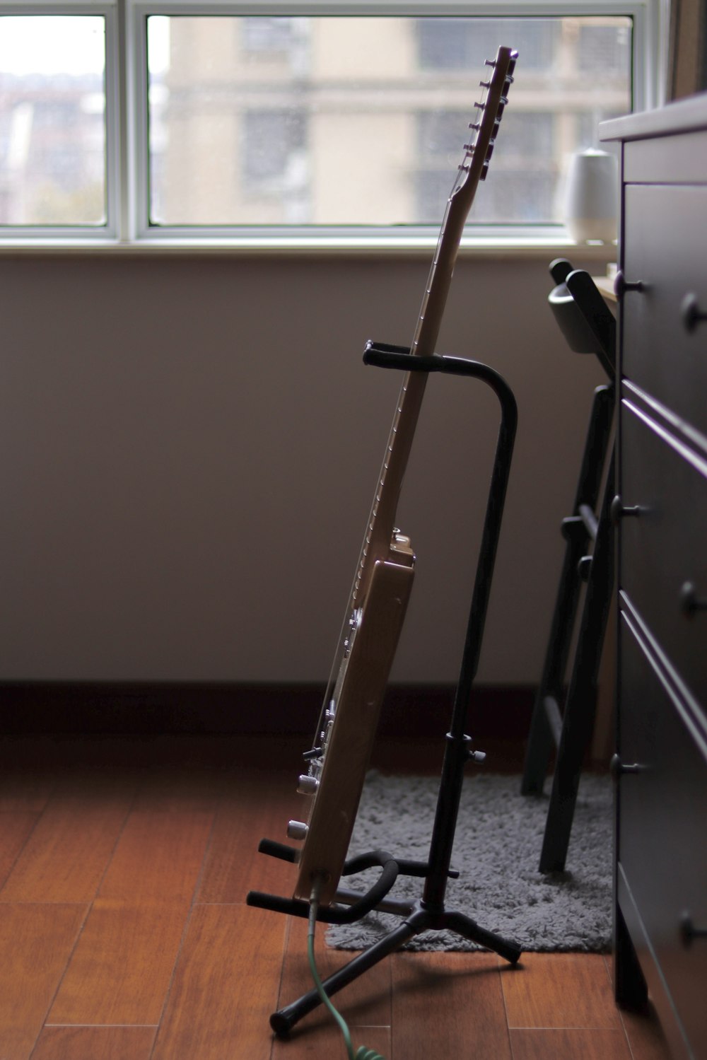 a guitar stand next to a window in a room