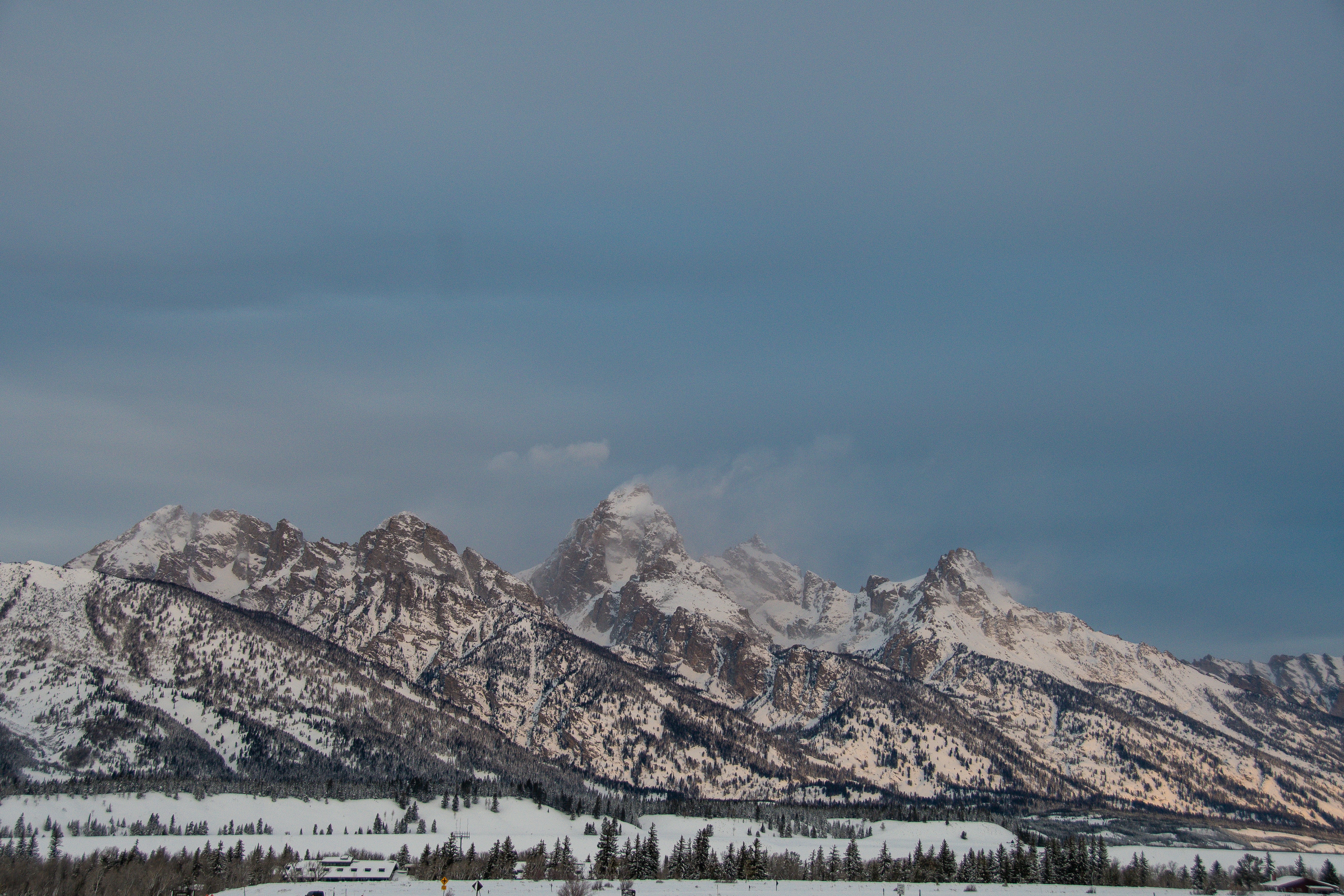 a snow covered mountain range under a cloudy sky