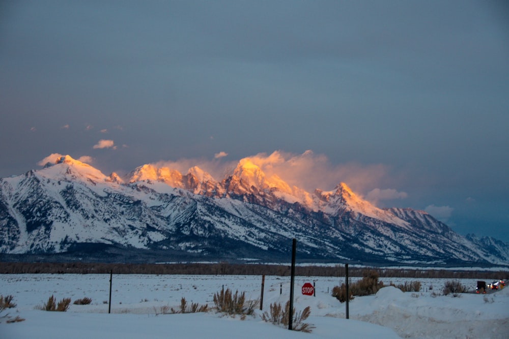 a snow covered mountain range with a stop sign in the foreground