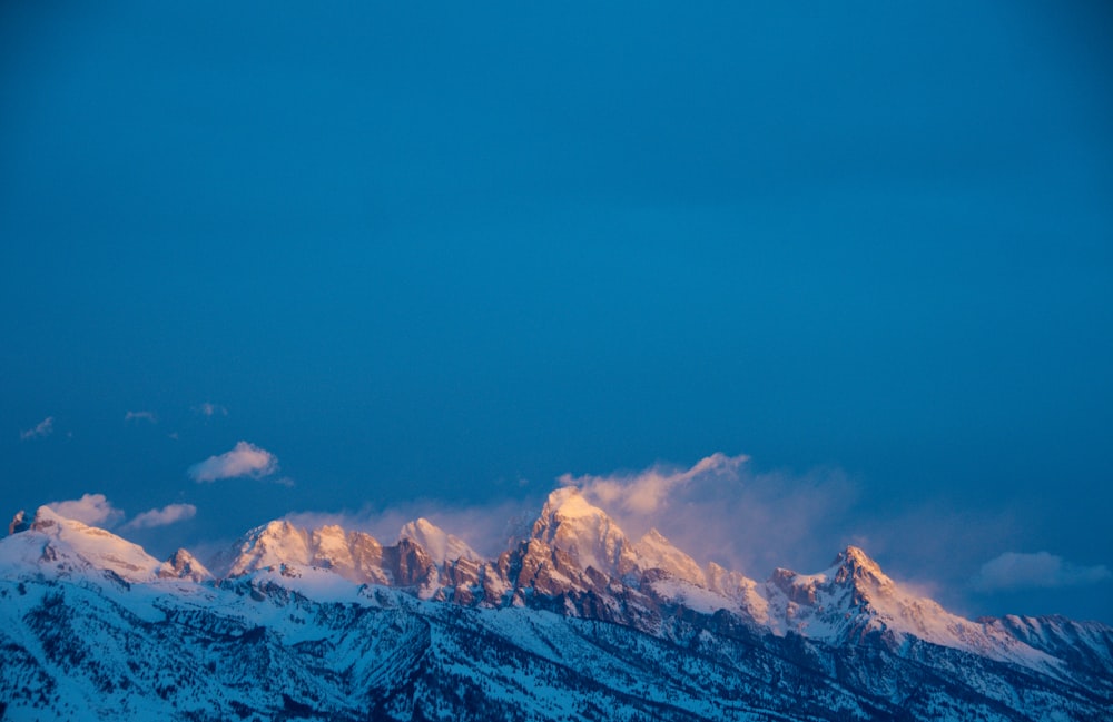 a view of a snowy mountain range at dusk