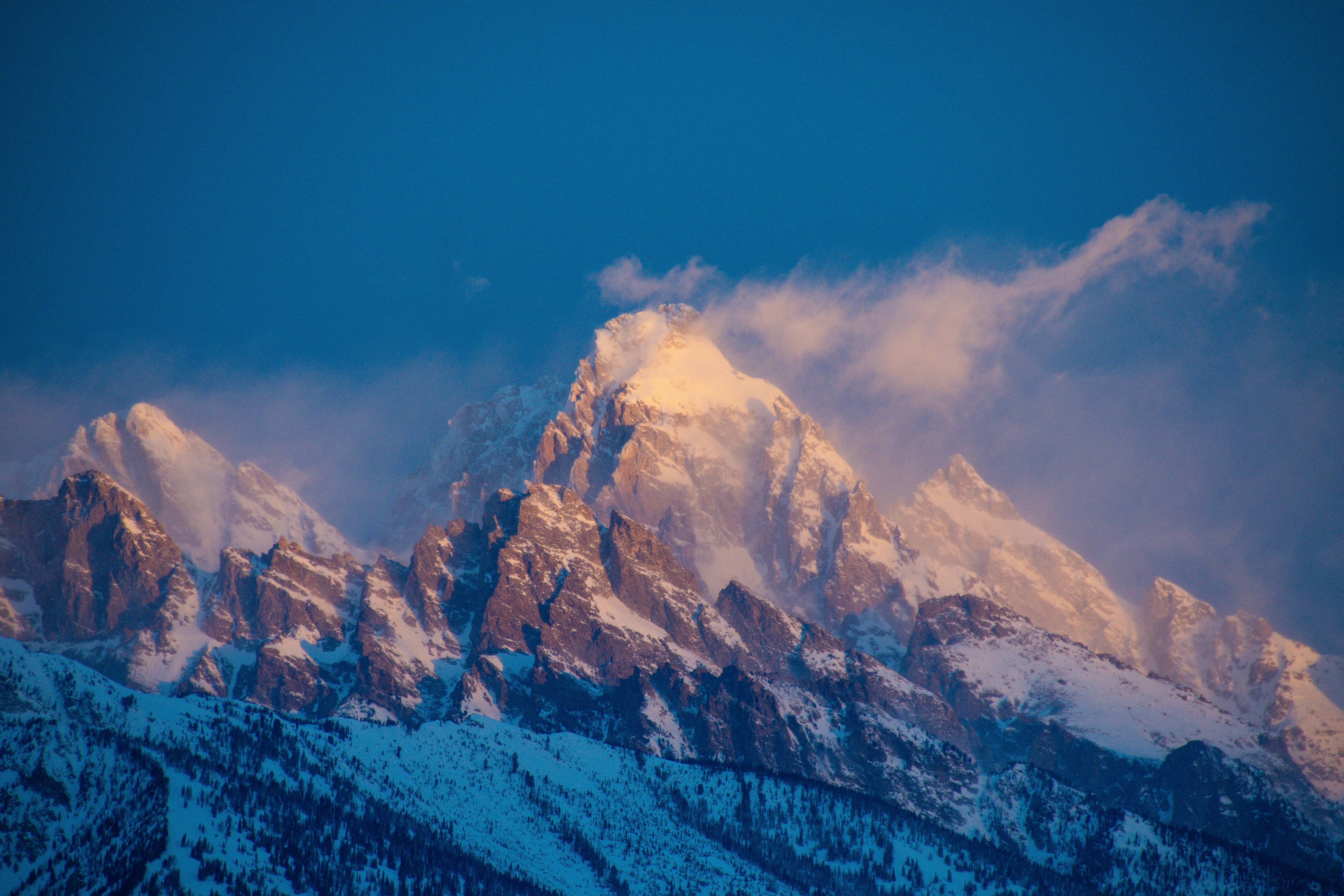 a mountain range covered in snow under a blue sky