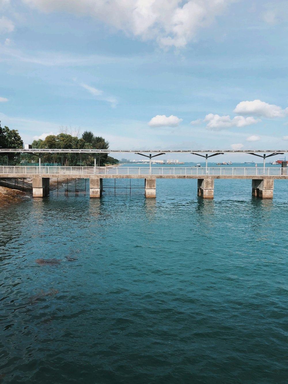 a bridge over a body of water under a cloudy blue sky