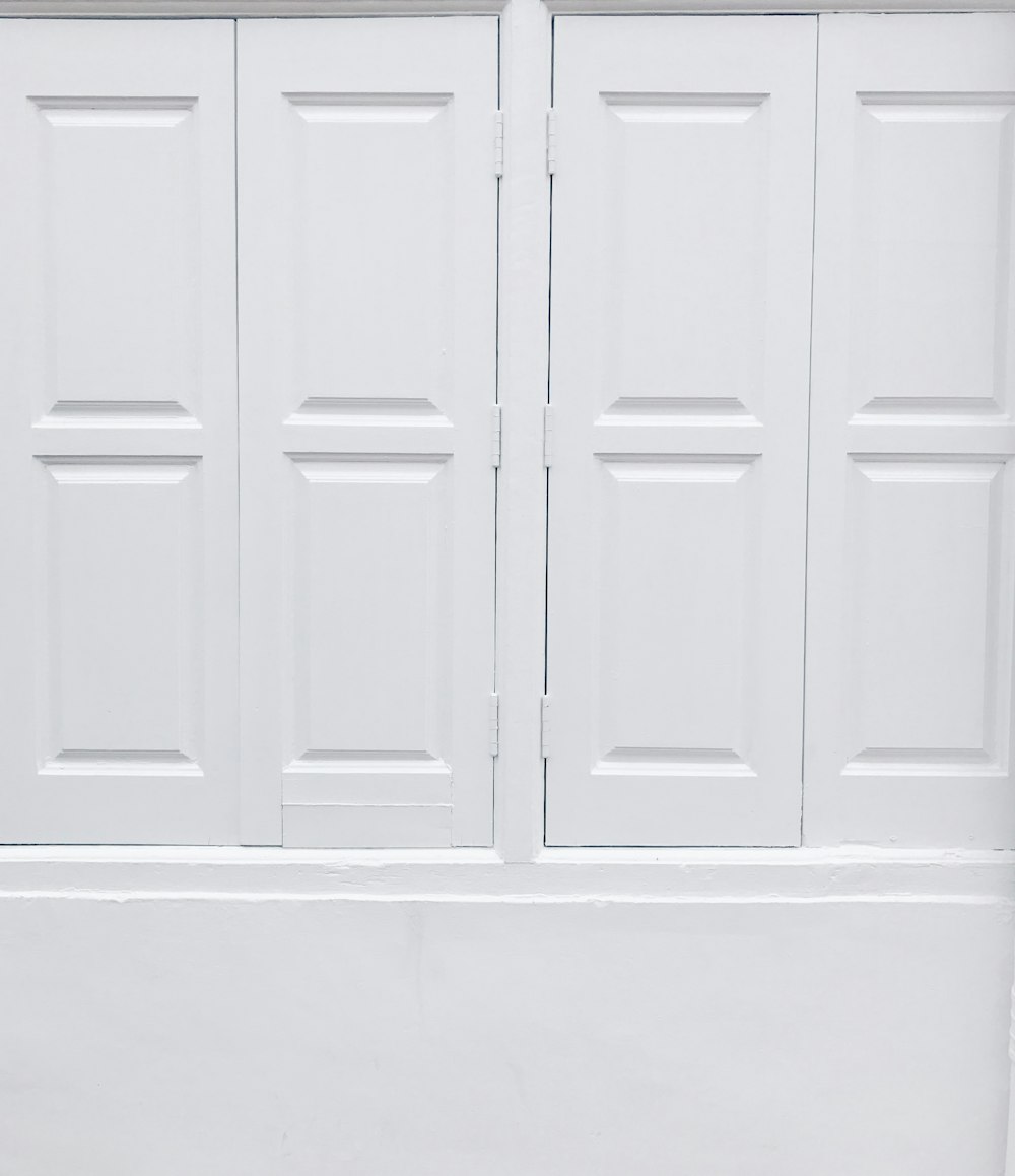 Eine schwarz-weiße Katze sitzt auf einer weißen Tür