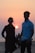 a man and a woman standing on a beach at sunset