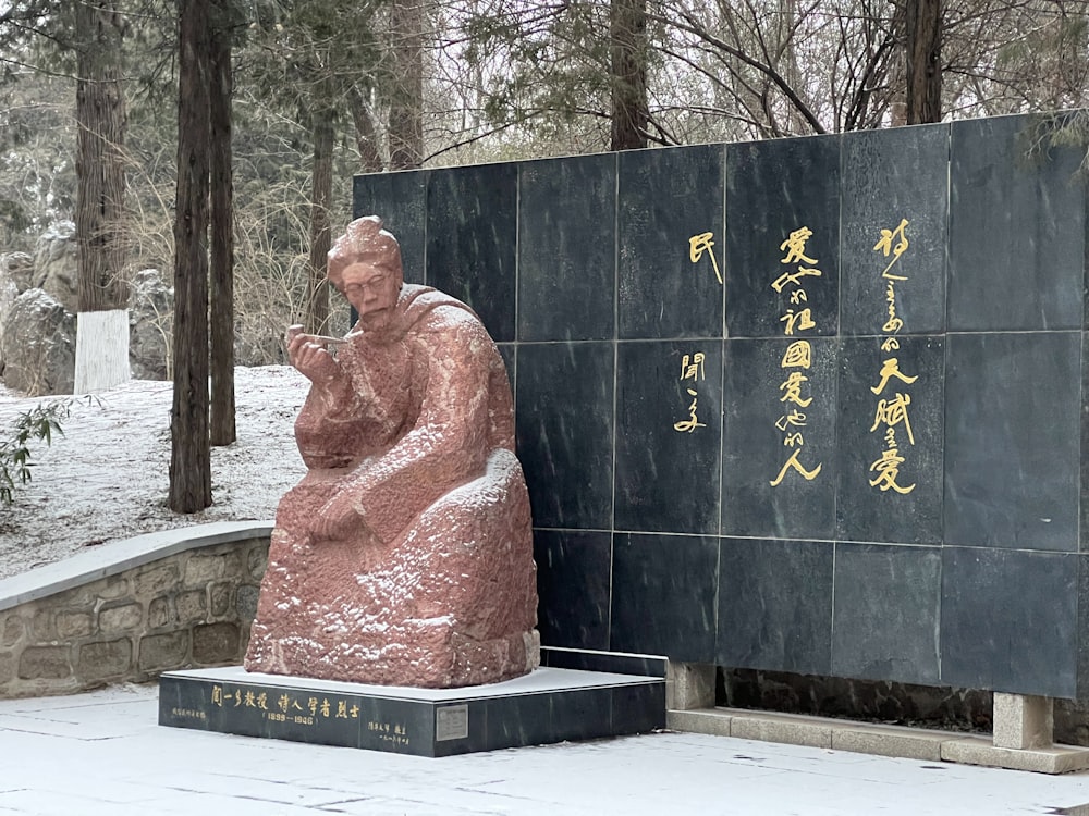 a statue of a person sitting in front of a wall