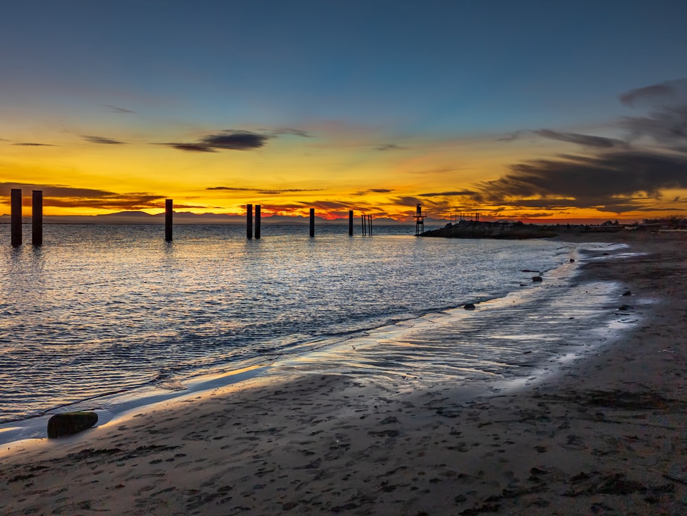 the sun is setting over the water at the beach