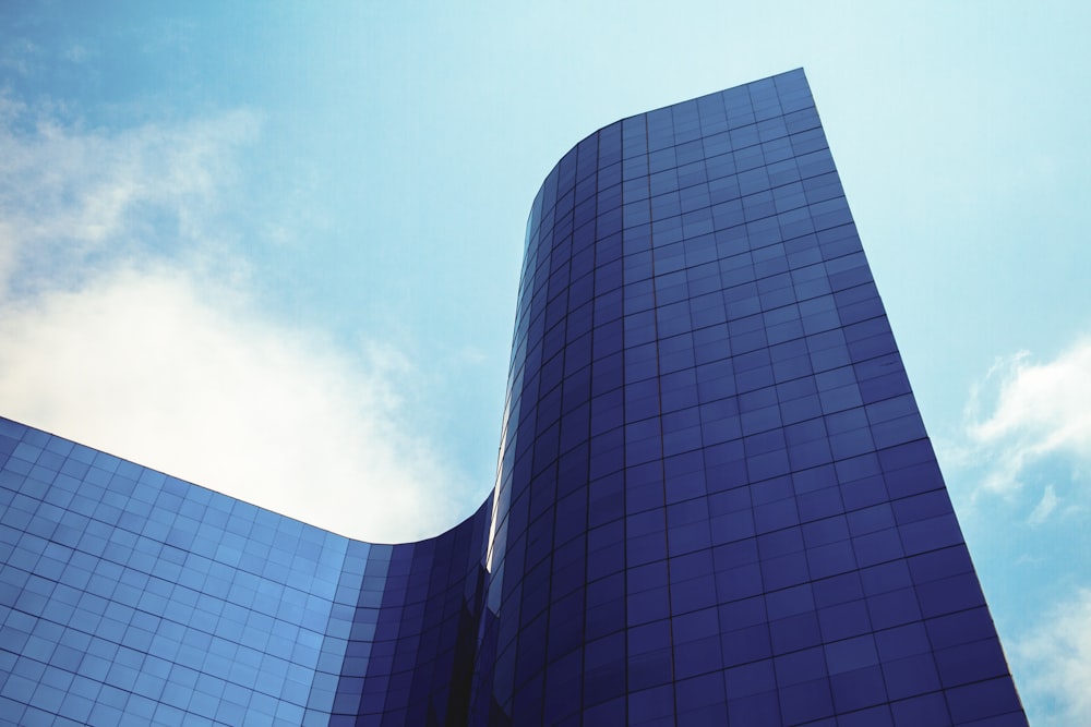 a tall blue building with a sky background