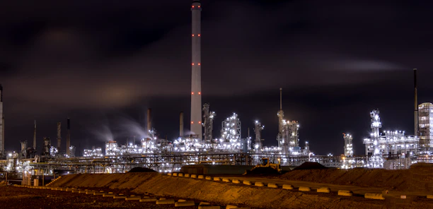 Oil refinery complex at sunset with workers inspecting equipment.