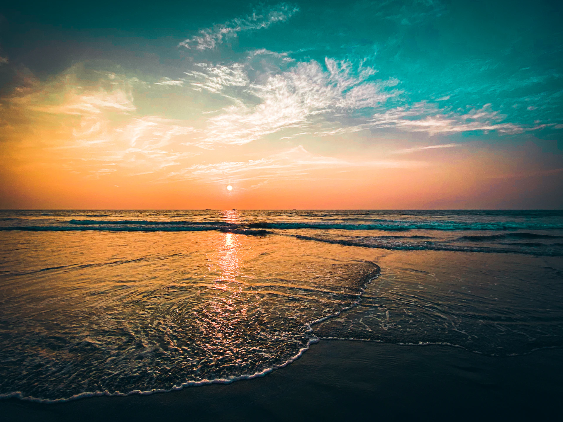 the sun is setting over the ocean on the beach