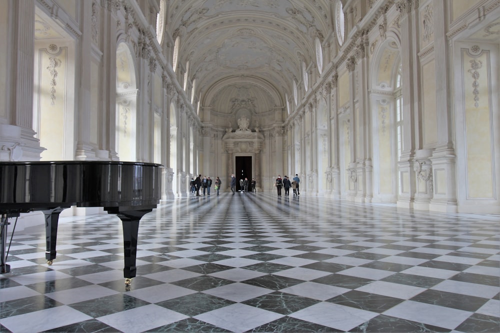 a grand piano in a large hall with a checkered floor