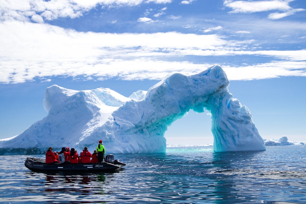 a group of people in a small boat in front of an iceberg
