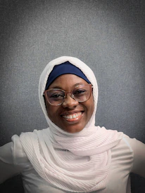 Close-up of a teacher smiling warmly during a live online Quran lesson.
