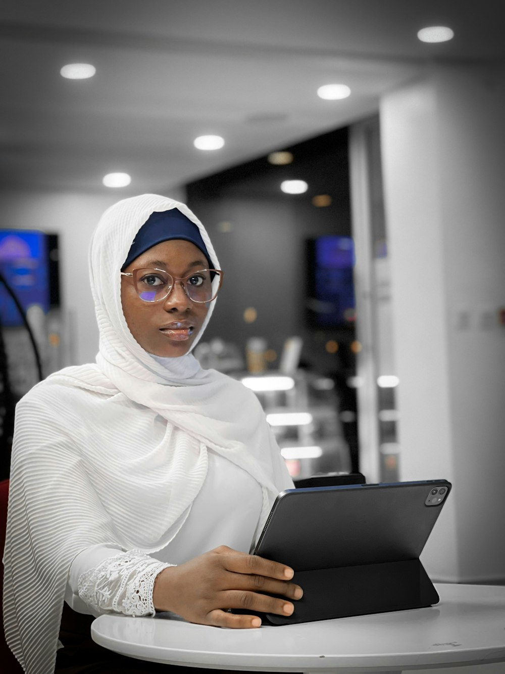 a woman sitting at a table with a tablet