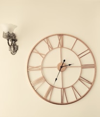 a clock on a wall next to a wall sconce